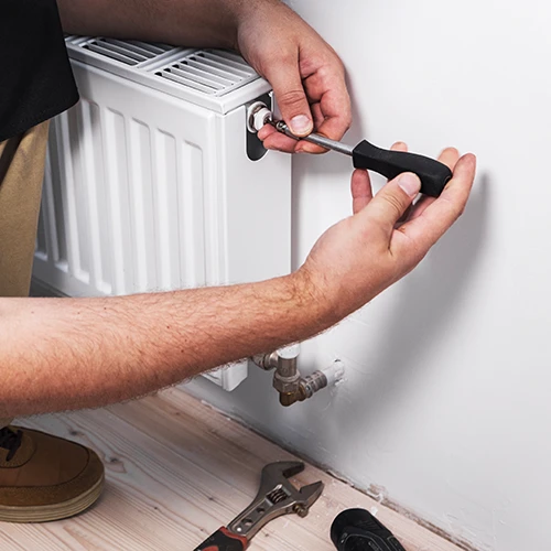 Heating engineer adjusting radiator valve during installation in a modern home